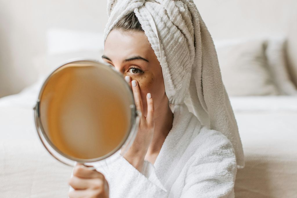 beauty routine per over 60 con pelle secca: donna che applica la crema mentre si specchia