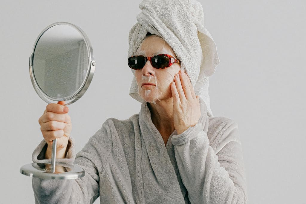 come avere un viso piu sodo e fresco dopo i 50 anni donna con maschera viso che si guarda allo specchio