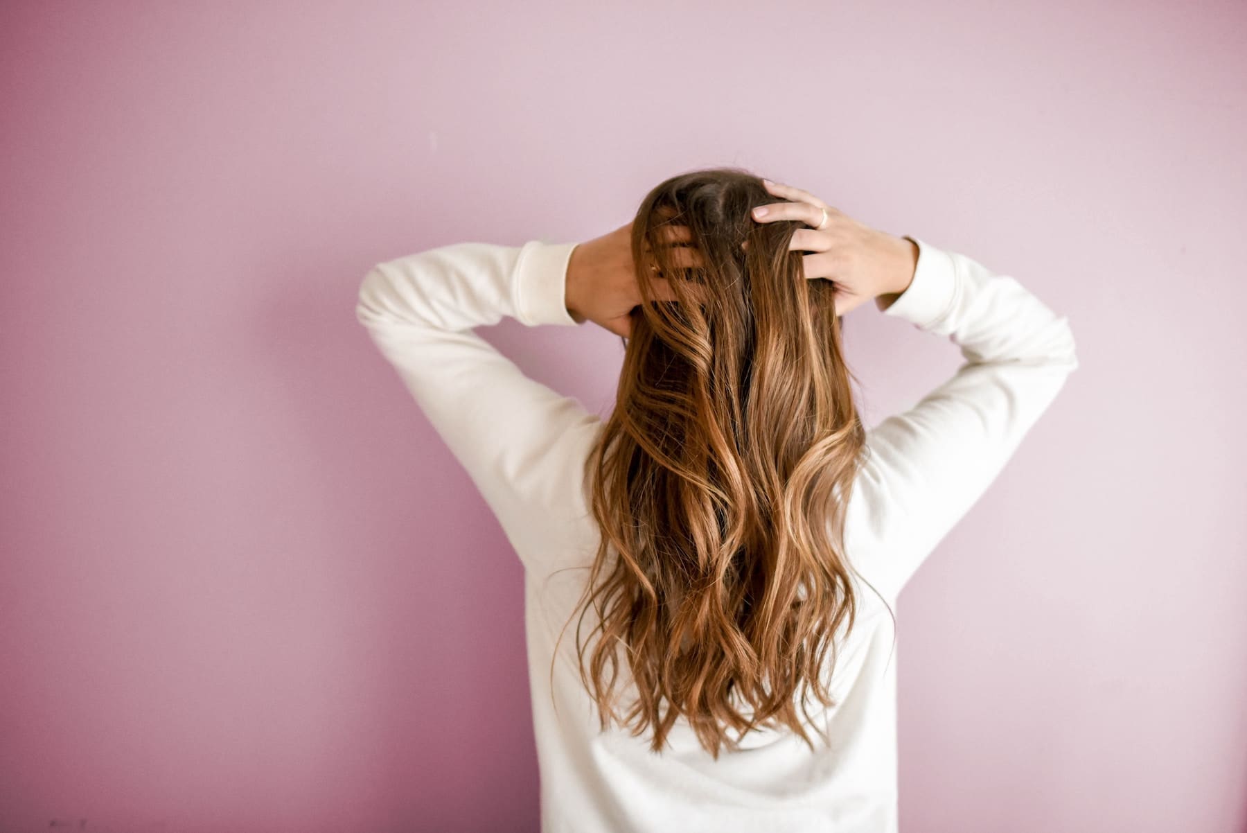cura dei capelli donna con capelli biondi lunghi che si massaggia