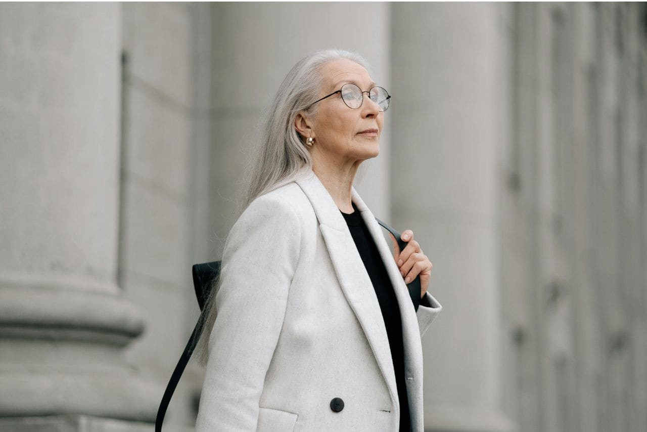 donna elegante con capelli grigi dopo i 60 e cappotto bianco