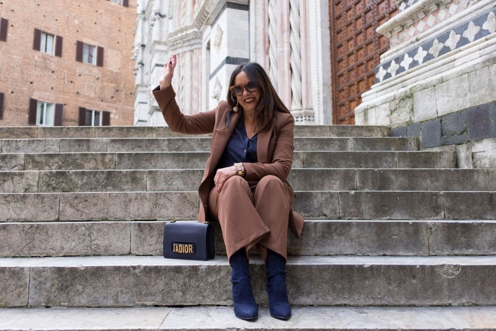 Donna over 60 con tailleur marrone e stivali blu, esempio di abbinamento marrone con blu elegante e moderno