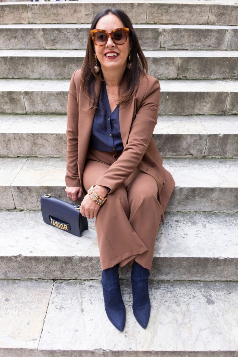 Donna over 60 con tailleur marrone e top blu notte, abbinamento elegante e senza tempo